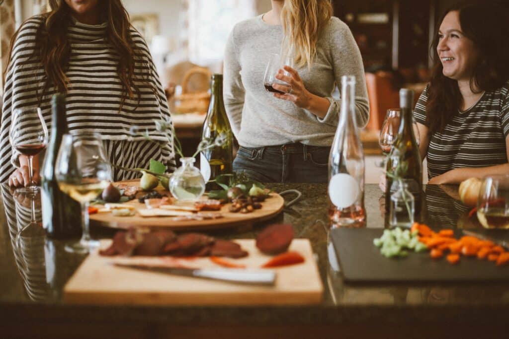 two woman standing beside woman sitting in front of table women eating