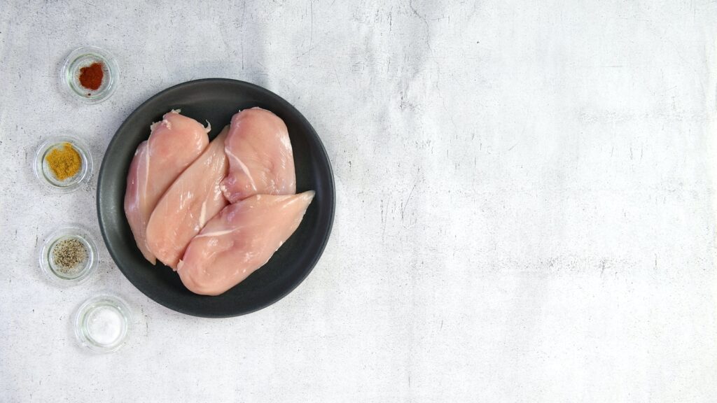 two raw chicken breasts in a black bowl