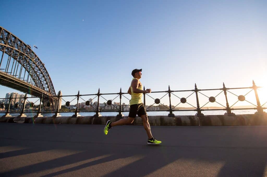 man in yellow tank top running near shore