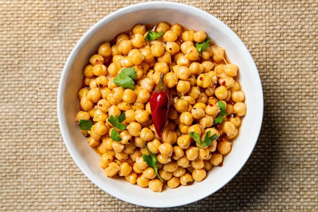 Chickpeas a white bowl filled with corn on top of a table